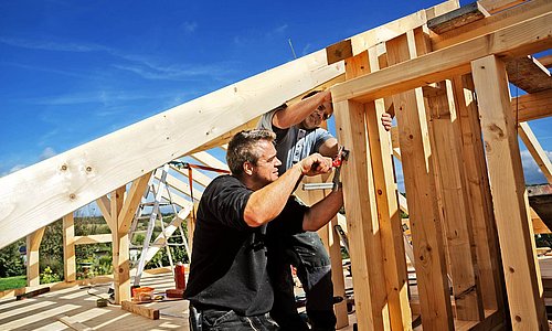 Arbeiter bei der Konstruktion eines Dachgrundgerüstes mit Holz