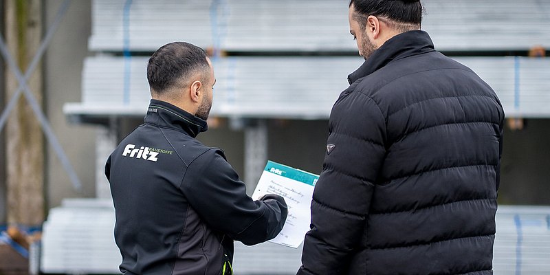 Ein Fritz Baustoffmitarbeiter steht neben einem Kunden