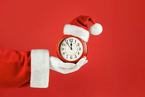 Weihnachtsmann der eine Uhr in der Hand hält