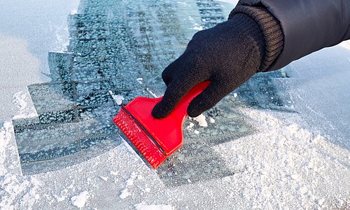 Eiskratzer auf zugefrorener Autoscheibe