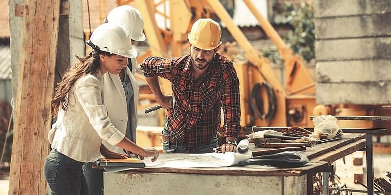 Handwerker und Handwerkerin mit Schutzhelmen auf einer Baustelle