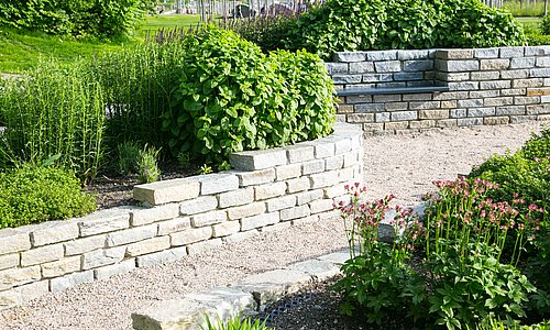 gepflasterter Gehweg zwischen einer grünen Wiese und Blumen